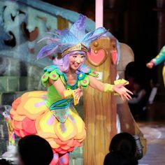 two women in colorful costumes on stage with one holding her hand out to the side