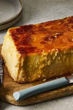 a piece of cheese cake sitting on top of a cutting board next to a knife