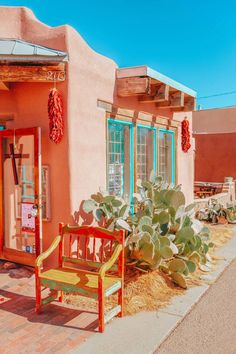 a bench sitting in front of a building next to a cactus and potted plant