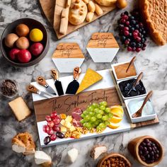 an assortment of cheeses, fruits and crackers on a marble table