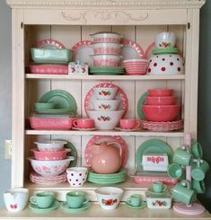 a china cabinet filled with lots of dishes and cups in pink, green and white