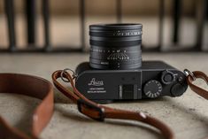 a camera sitting on top of a table next to a brown strap