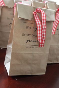 brown paper bags with red and white checkered ribbon tied around them on a table