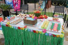 a table topped with lots of food on top of a lush green field next to a fence