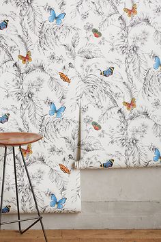 the wall paper has butterflies on it and is next to a stool in front of an empty room