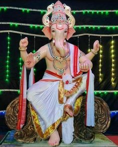 an elephant statue sitting on top of a wooden platform in front of a string of lights