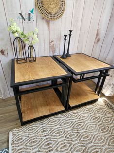 two tables sitting on top of a rug in front of a wooden wall with vases