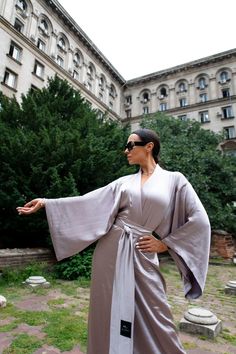 This Japanese elegant dress in a soft lilac shade is the epitome of refined style and comfort. Designed as a long kimono robe, it features a luxurious satin finish that drapes beautifully, offering both sophistication and ease. The satin kimono dress serves as a versatile piece, perfect for lounging or special occasions. Ideal as a gift for her, this comfortable satin robe is a thoughtful choice for any woman who appreciates both elegance and relaxation. Its unique blend of style and comfort mak Satin Kimono Dress, Kimono Dress Outfit, Kimono Street Style, Japanese Inspired Fashion, Japanese Kimono Dress, Japanese Fashion Trends, Kimono Styles, Elegant Kimono, Modern Kimono