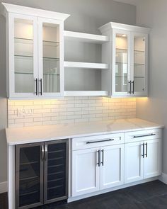 an empty kitchen with white cabinets and glass doors on the cupboards are lit by recessed lights