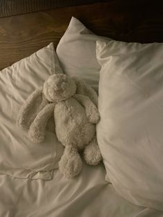 a white stuffed animal sitting on top of a bed