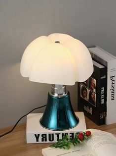 a blue lamp sitting on top of a table next to a book and an open book