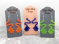 three pairs of handmade earrings in different colors and shapes, on display next to each other