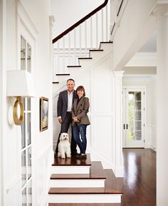 a man and woman standing on the stairs with their dog