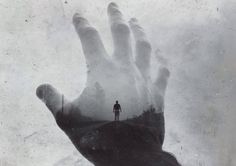 a person standing on top of a hill with their hand in the air and fog