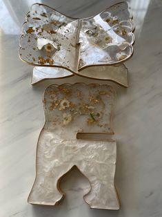 three pieces of white and gold glass on a marble counter top with flowers in the middle