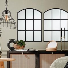 a living room with two windows and a plant on the side table in front of it