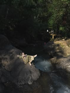 a man on a rock in the middle of a river