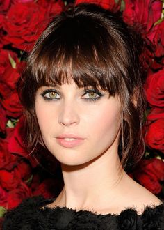 a close up of a person with short hair and green eyes wearing a black dress