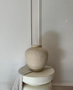 a white vase sitting on top of a stack of stools