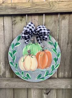 a painted plate with three pumpkins on it and a bow hanging from the front