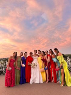 a group of women standing next to each other in front of a pink and blue sky