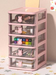 a pink plastic drawer with lots of crafting supplies in it on top of a table