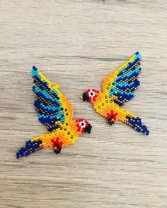 two colorful birds made out of beads on a wooden surface