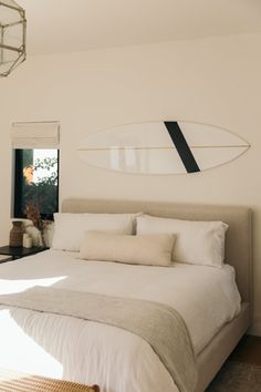 a bedroom with a surfboard mounted to the wall above the headboard and bed