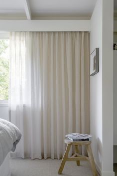 a bed room with a neatly made bed and a white curtain hanging on the wall