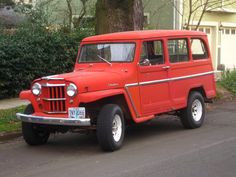 an old red jeep is parked on the side of the road in front of a house