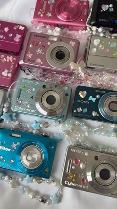 there are many different types of cameras on the table together with beads and pearls all around them