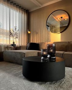 a living room filled with furniture and a round mirror on the wall above it's coffee table