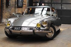 an old grey car parked in front of a building