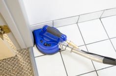 a blue and black blow dryer sitting on top of a white tiled floor next to a door