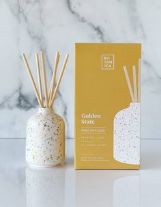 the golden state reed diffuser is next to a box with gold sprinkles on it