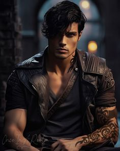 a man with tattoos on his arm sitting in front of a brick wall and wearing a leather jacket