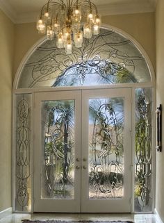 an ornate entryway with two glass doors and chandelier above the entrance door