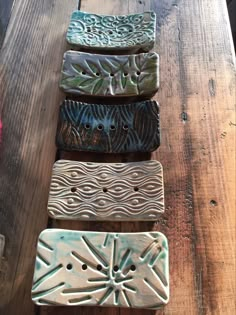 four different colored ceramic plates sitting on top of a wooden table