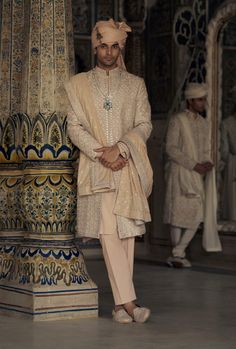 Elevate your style in this peach raw silk sherwani, featuring intricate all-over silver zari and mirror embroidery, highlighted with dabka and beadwork. Accompanied by a cotton silk kurta and trouser, it comes with chanderi booti stole. Luxury Ceremonial Sherwani With Mirror Work, Elegant Sherwani With Mirror Work, Designer Fitted Sherwani With Mirror Work, Traditional Silk Sherwani With Mirror Work, Luxury Semi-stitched Sherwani With Mirror Work, Modern Groom, Indian Wedding Wear, Mirror Work, Wedding Wear