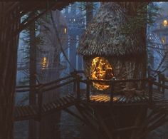 a tree house in the middle of a forest at night with lights coming from it