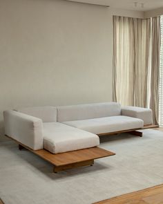 a white couch sitting on top of a wooden table in front of a large window