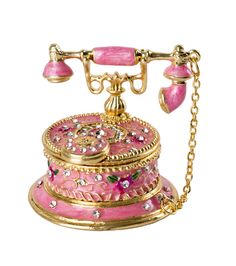 an old fashioned pink and gold phone on a chain with two bells attached to it