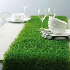 the table is set with white dishes and green grass