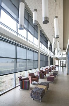 an empty waiting area with many chairs and windows in the background, along with several benches lined up against the wall