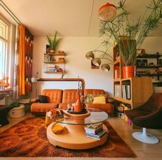 a living room filled with lots of furniture and plants on the wall next to a window