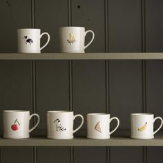 five coffee mugs with different designs on them are lined up in a row against a wall