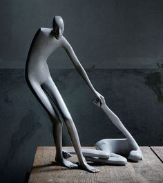 a white mannequin standing on top of a wooden table next to a bowl