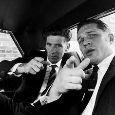 two men sitting in the back seat of a car pointing at something with their fingers