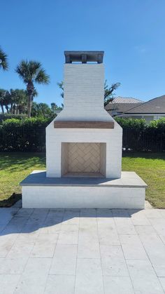 a white brick oven sitting in the middle of a yard with palm trees behind it