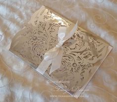 the inside of a wedding card with a white bow on it's side, sitting on a bed